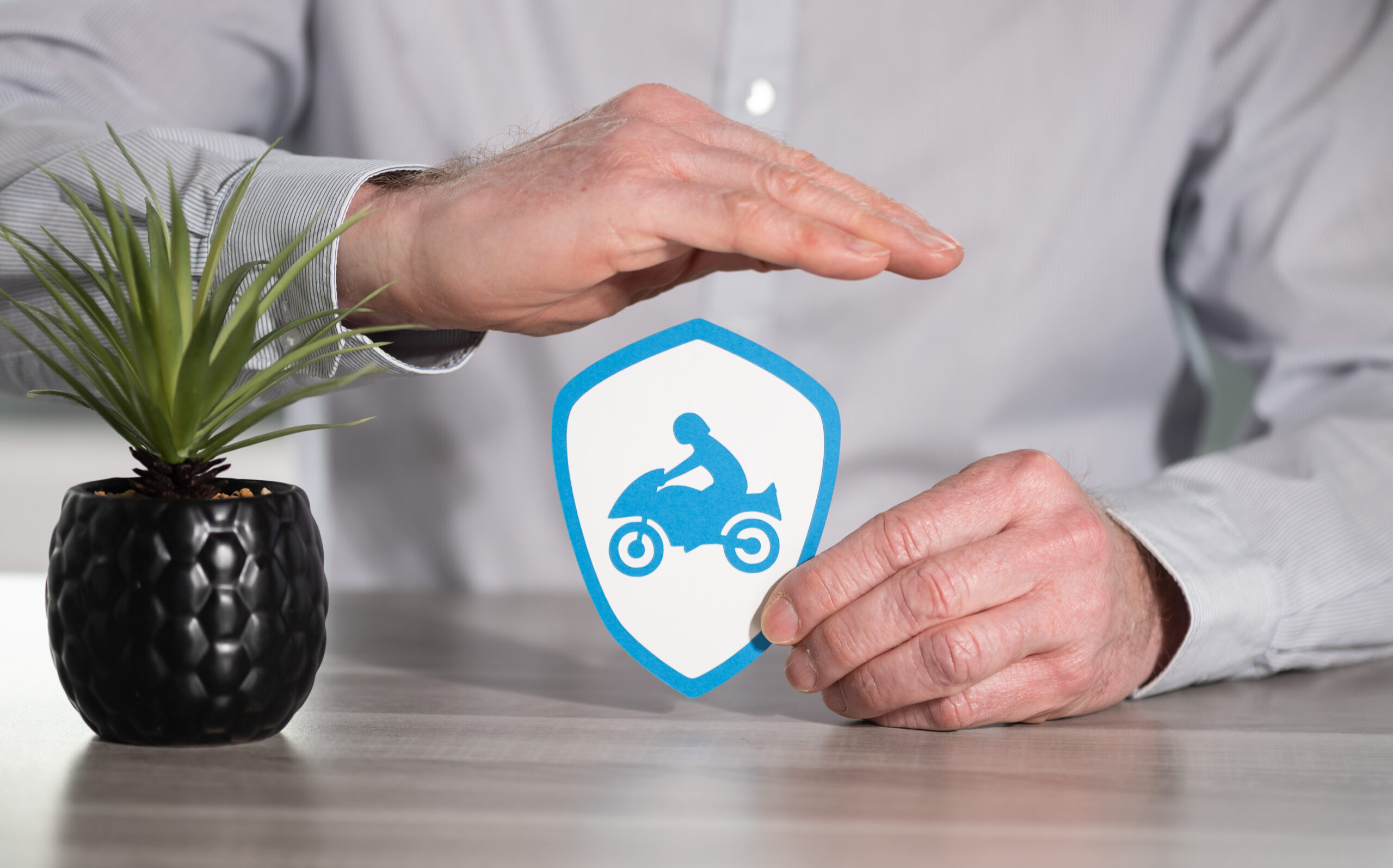 Concept,Of,Motorbike,Insurance,With,Paper,Shield,Protected,By,Hand